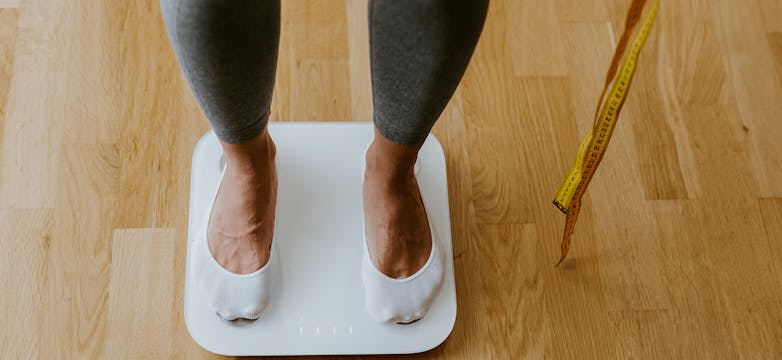 woman on weighing scales holding a measuring tape