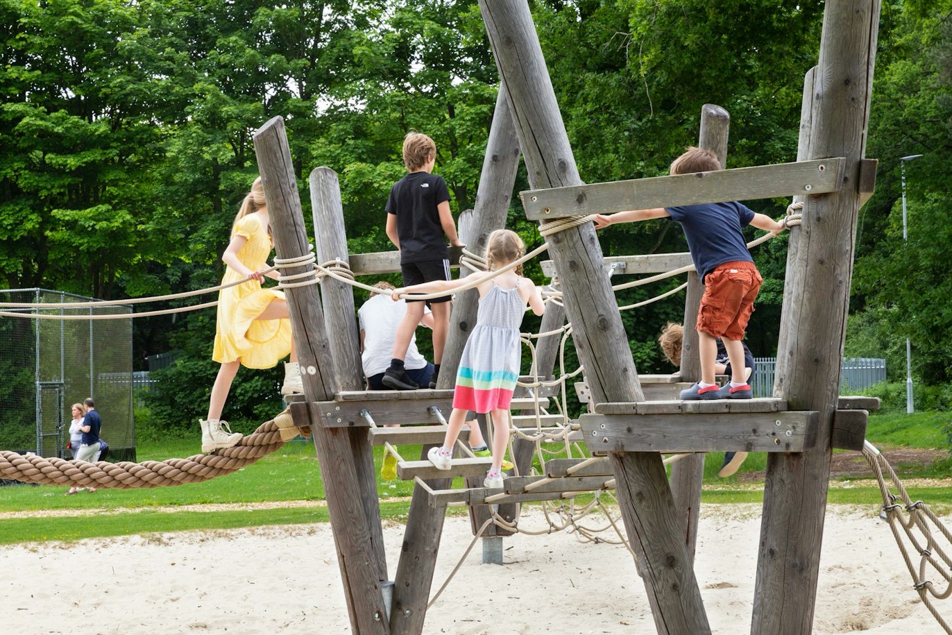 Children climbing on a wooden play frame in an outdoor play area