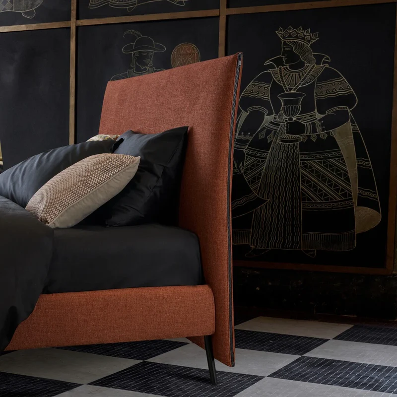 Bed with orange fabric headboard and dark cushions