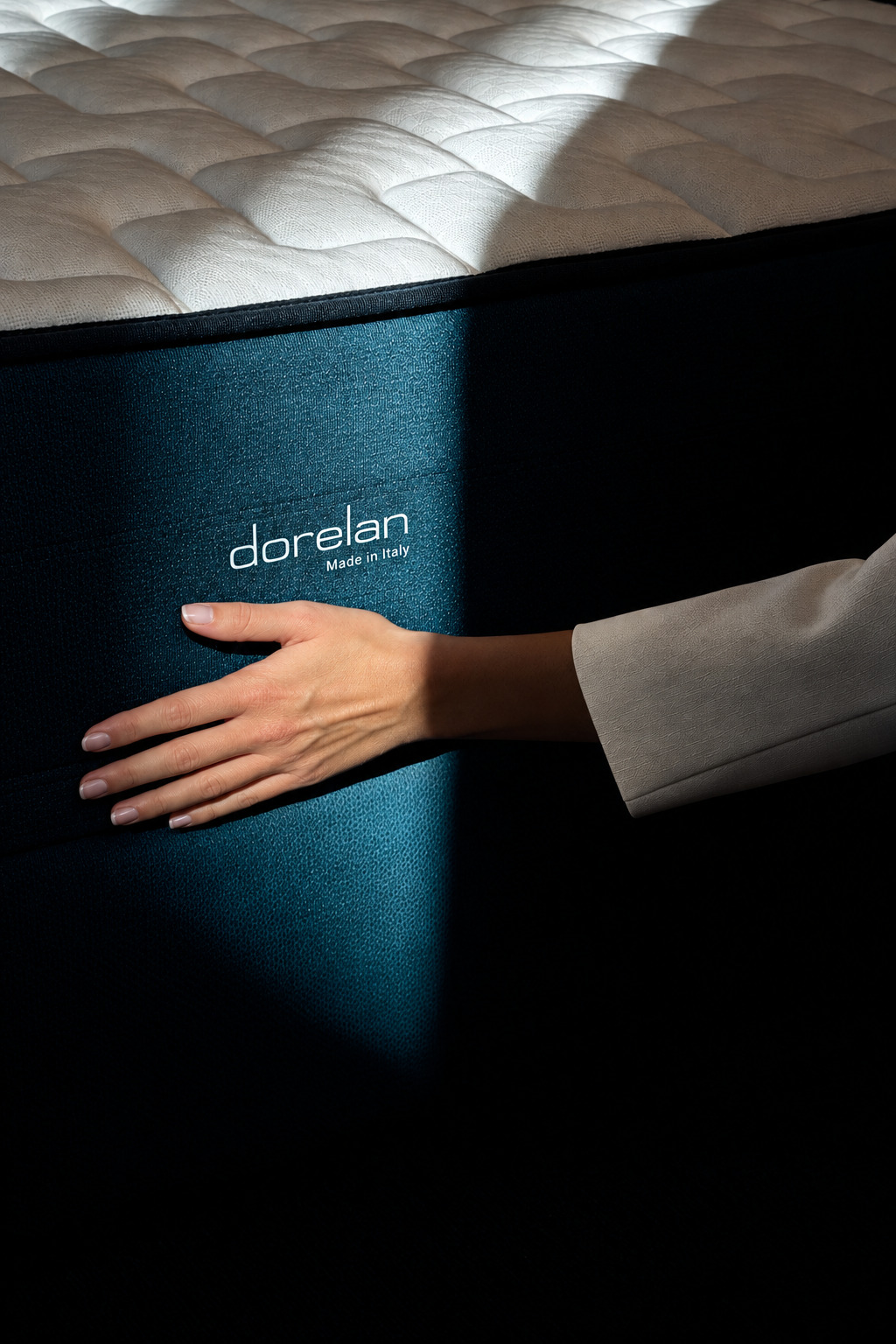 Hand resting on the side of a Dorelan mattress lit by a beam of light