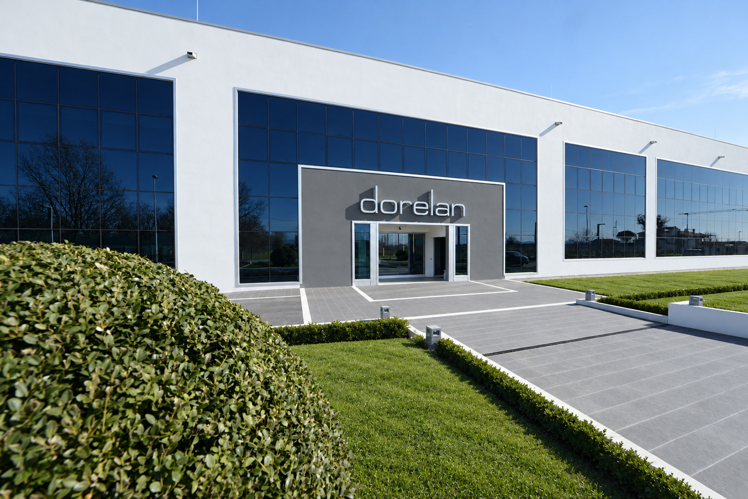 Entrance of the Dorelan headquarters with glass façade and garden
