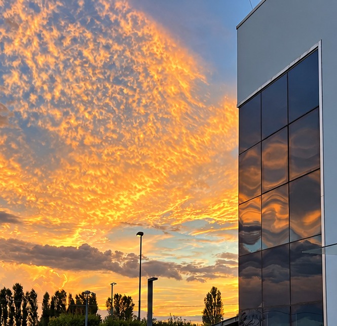 Glass façade of the Dorelan headquarters against a sunset sky