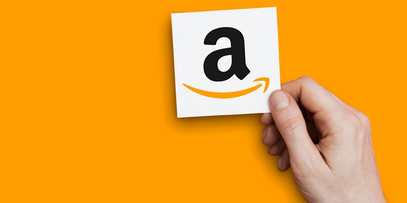 un main qui tient un papier avec le A du logo Amazon