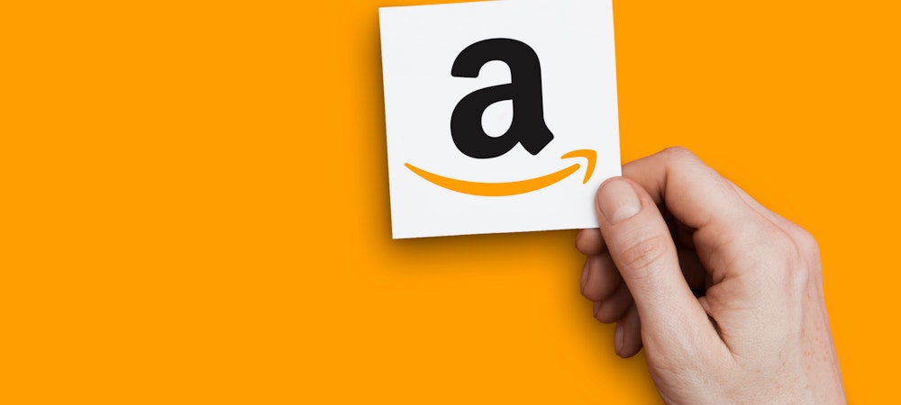 a hand holding a paper with the A of the Amazon logo