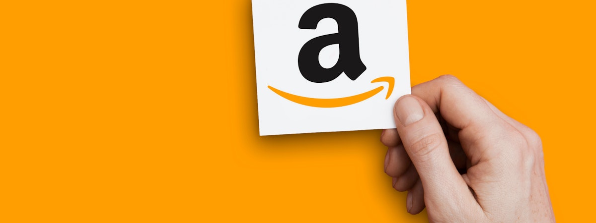 un main qui tient un papier avec le A du logo Amazon