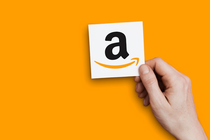 a hand holding a paper with the A of the Amazon logo