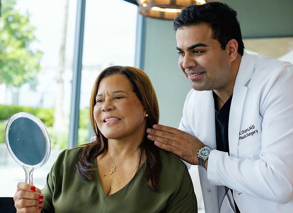 Dr. Chopra with patient both looking in handheld mirror