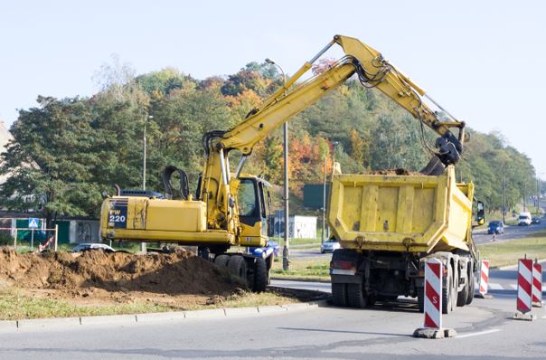 Koparka kopie dół z ciężarówką pod kanały technologiczne