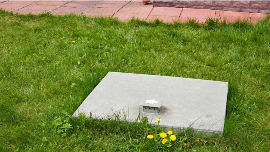 Concrete cover for a septic tank on the lawn of the plot