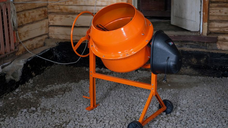 Orange concrete mixer on rocky ground inside the building