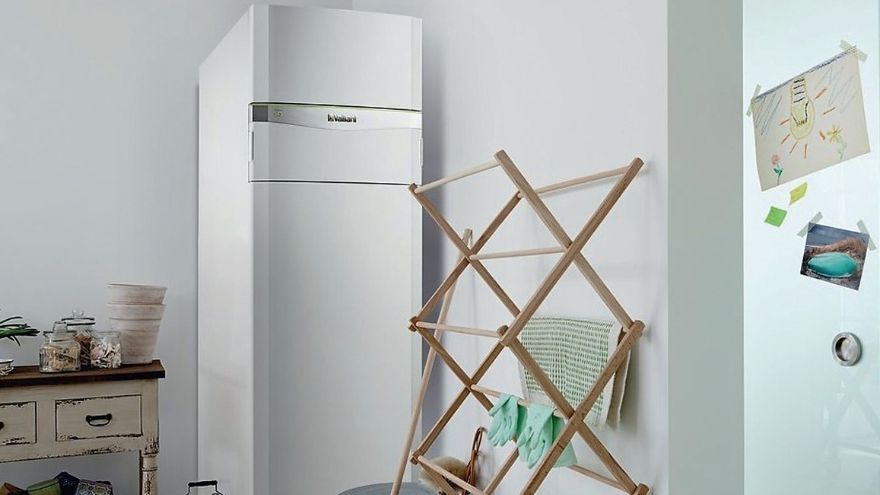 Внутрішній блок теплового насоса Vaillant в білому корпусі, встановлений в підсобному приміщенні будинку, поруч з сушаркою для білизни.