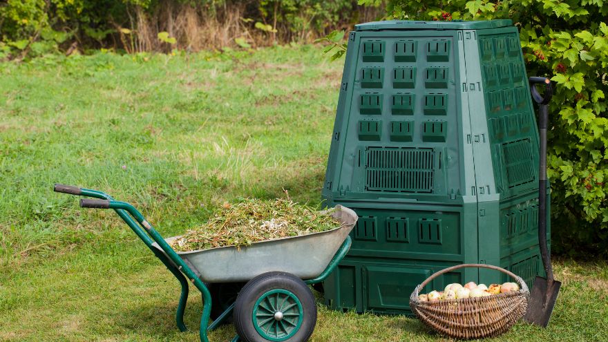 Kompostownik ogrodowy i taczka stojące w ogrodzie przydomowym