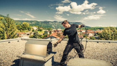 Kominiarz czyści komin na dachu płaskim