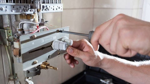 Instalator ze śrubokrętem naprawia rozebrany ogrzewacz wody