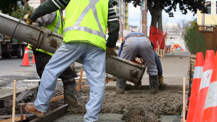 Pracownicy budowlani układają i wyrównują beton w ramach projektu odnowy chodnika