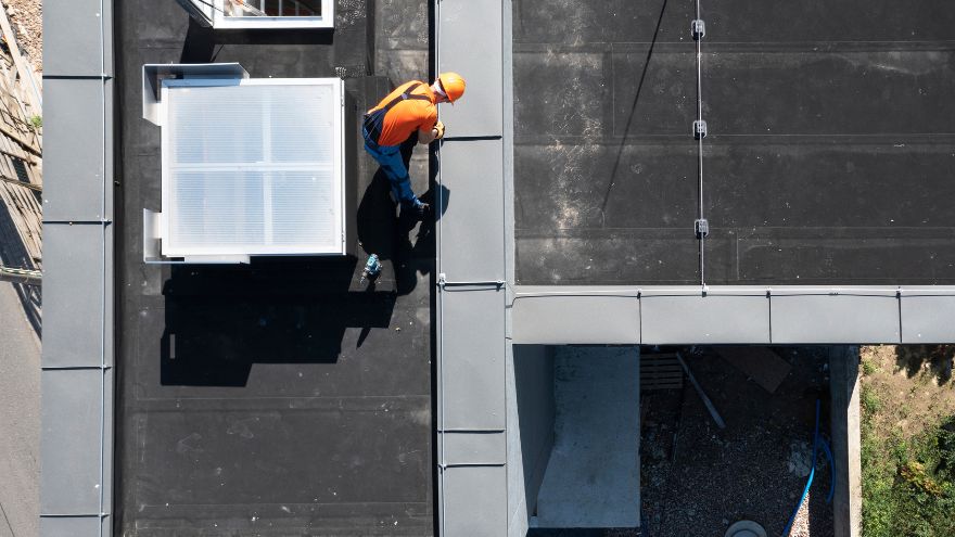 Technik naprawia instalację odgromową na płaskim dachu