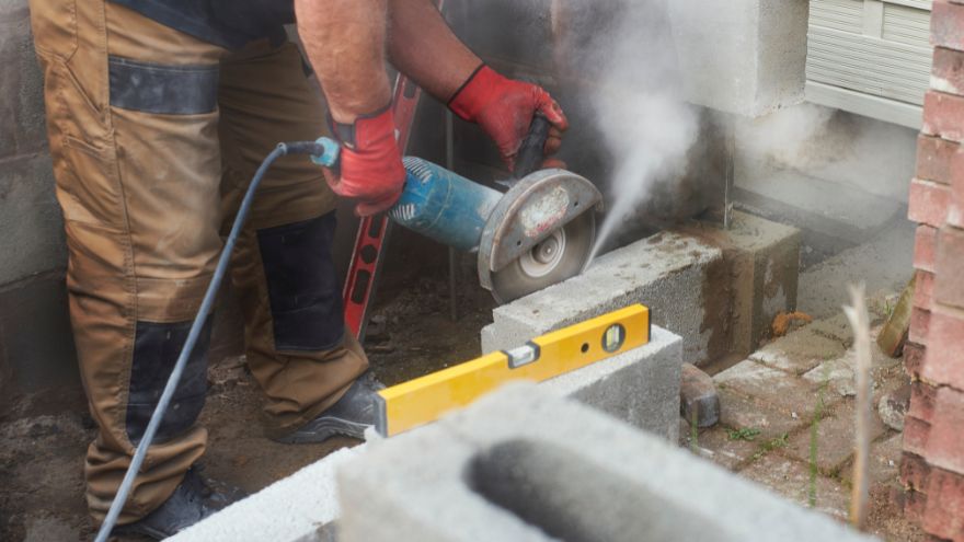 Pracownik fizyczny przecina beton na budowie