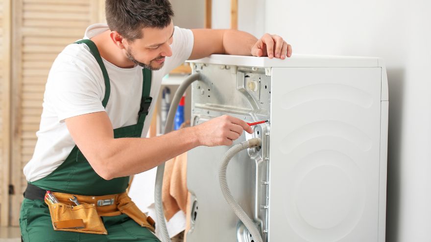 Монтажник ремонтує пральну машину Instalator naprawia pralkę