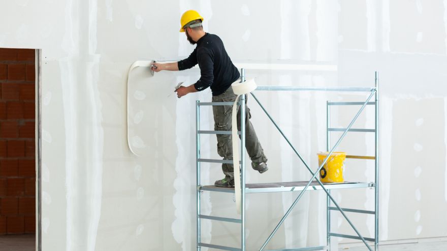 Pracownik wykończeniowy wykańcza ścianę na rusztowaniu