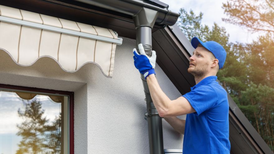 Instalator montuje sztucer do rynny w domu jednorodzinnym