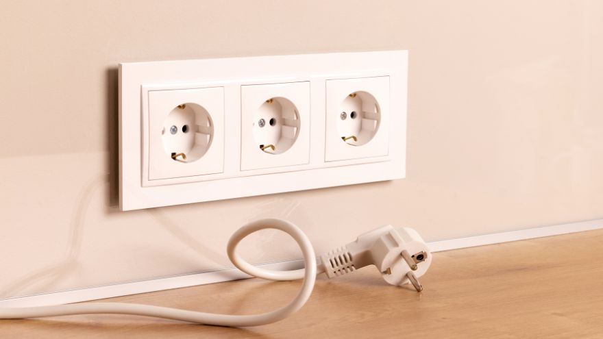 Białe gniazda elektryczne w ścianie z kablem