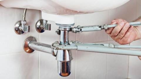 Vodoinstalater zašrafljuje koleno ispod umivaonika sa ugaonim ventilima