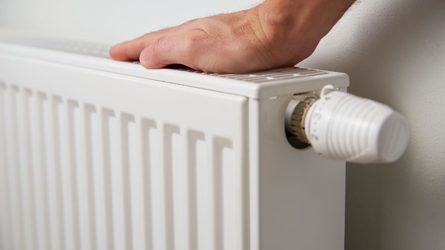 Mężczyzna sprawdza temperaturę stalowego grzejnika na ścianie