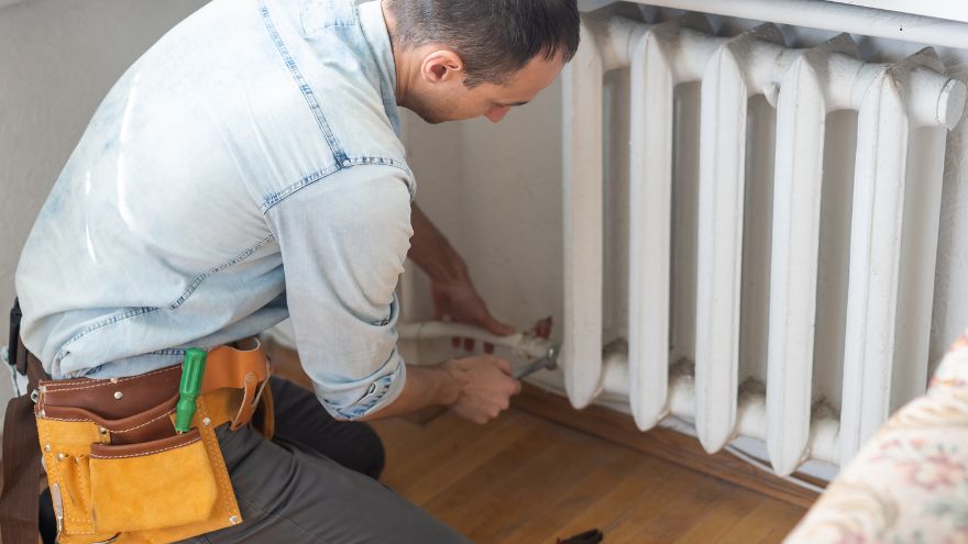 L'installateur répare un radiateur en fonte dans le salon Instalator naprawia żeliwny grzejnik w salonie
