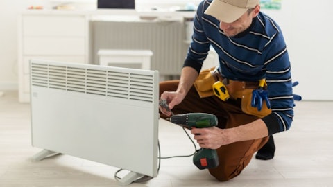 The installer installs an electric heater in the living room with a thermostat
