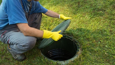 A septic tanker opens the hatch to a septic tank in the garden