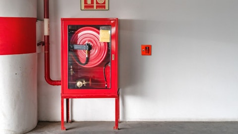 Hydrant wolnostojący ze sprzętem gaśniczym i skrzynką na klucz ewakuacyjnym na białej ścianie