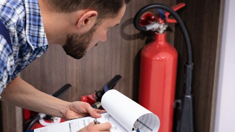 Technik pożarnictwa sprawdza zabezpieczenia przeciwpożarowe w budynku usługowym