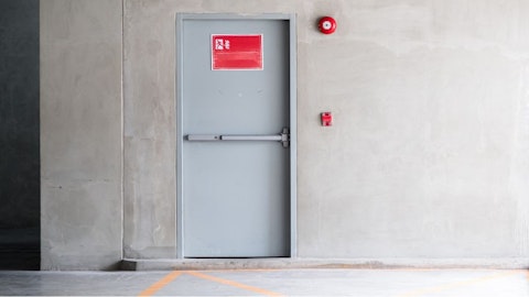 Drzwi ewakuacyjne w podziemnym garażu z przyciskiem ewakuacyjnym na ścianie