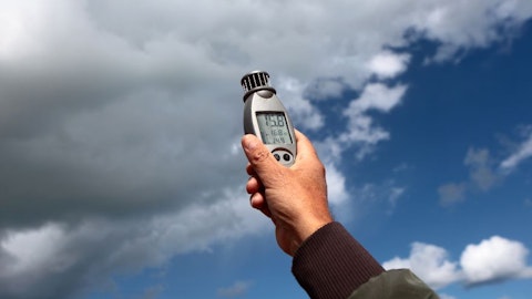 Technik mierzy właściwości powietrza i pogody na zewnątrz z termoanemometrem na tle nieba