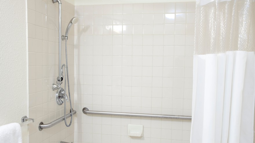 Łazienka z wanną i zestawem prysznicowym i drążkami do podpierania