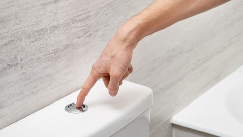 Męzczyzna spłukuje wodę przyciskiem do spłukiwania wody WC w łazience