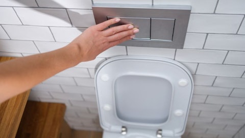 Kobieta spłukuje miskę WC podtynkowym przyciskiem do spłuczki w łazience