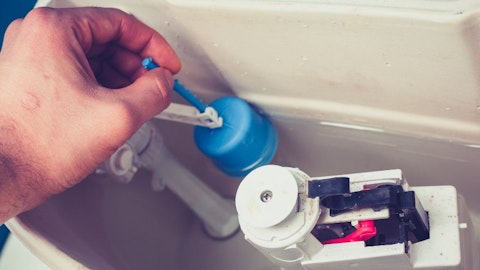 Instalator w łazience naprawia zepsuty zawór spłukujący z spłuczce od WC