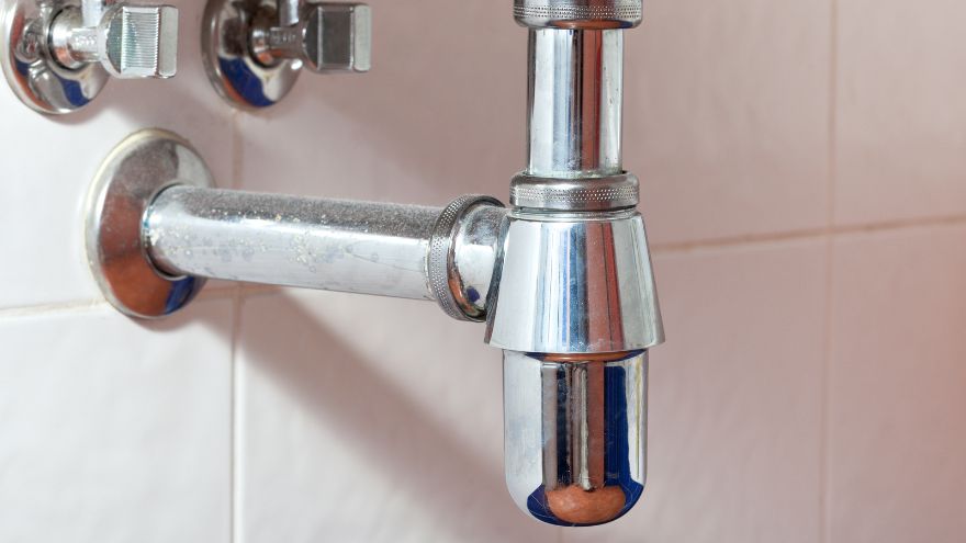 Chromowany syfon kulowy do pisuaru w łazience na ścianie