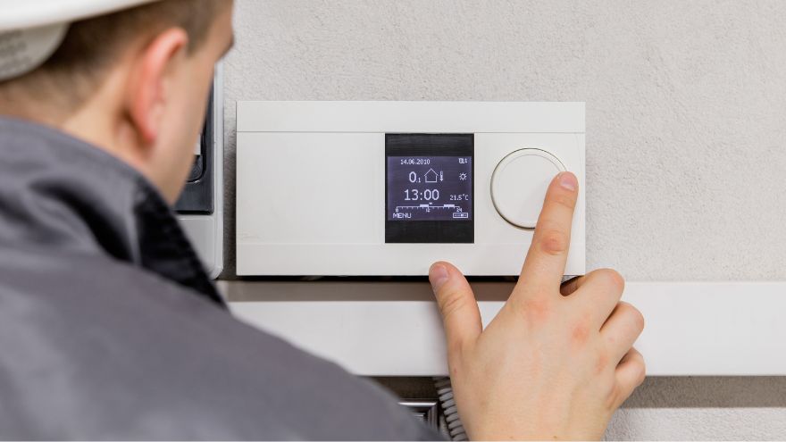 Instalator reguluje temperaturę w pomieszczeniu sterownikiem ogrzewania