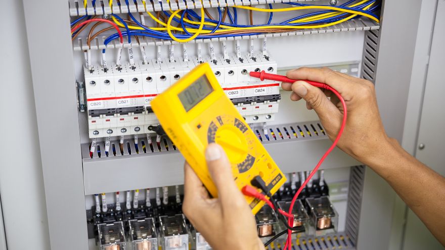 Instalator sprawdza napięcie w rozdzielnicy elektrycznej przy szafce rozdzielczej