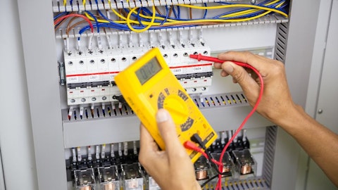 Instalator sprawdza napięcie w rozdzielnicy elektrycznej przy szafce rozdzielczej