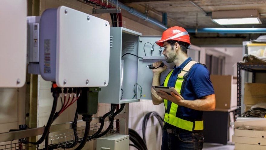 Instalator sprawdza sterownik energii elektrycznej w budynku użyteczności publicznej