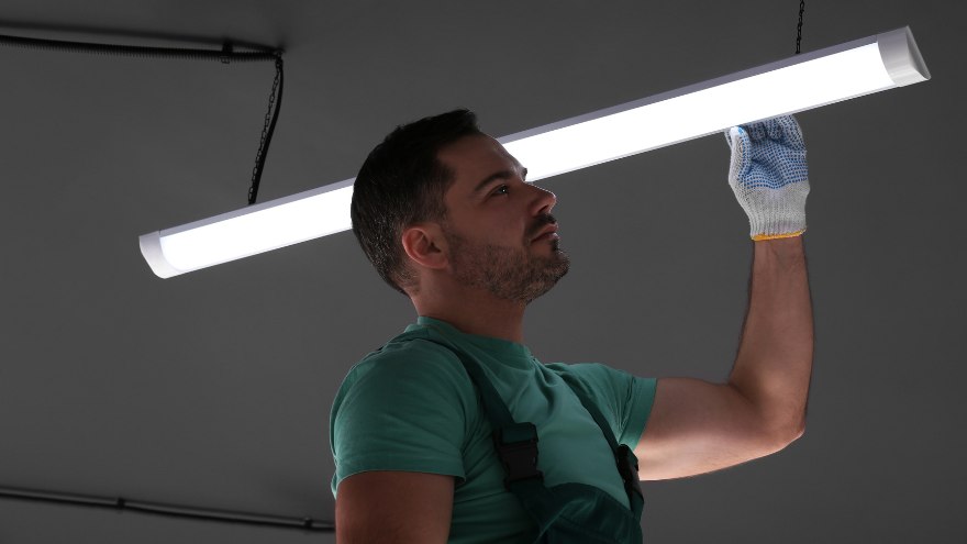 Instalator montuje świetlik LED w ciemnym pokoju