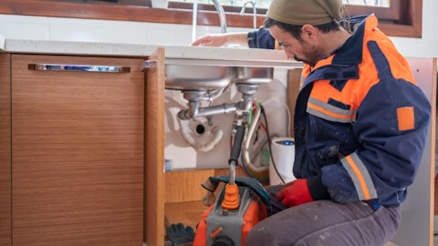 Hydraulik naprawia zapchany i śmierdzący zlew w kuchni z maszyną do przepompowywania nieczystości