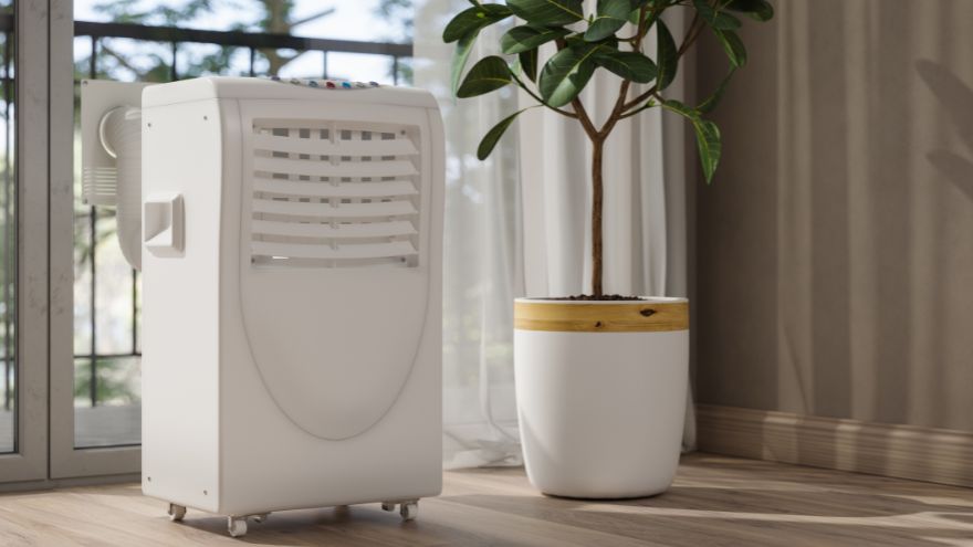Klimatyzator przenośny na kółkach z rurą w salonie z rośliną przy balkonie