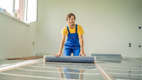 Instalator kładzie folię grzewczą w pokoju w stanie surowym w mieszkaniu