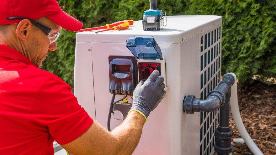 Instalator montuje pompę ciepła w ogrodzie z nowoczesnymi akcesoriami