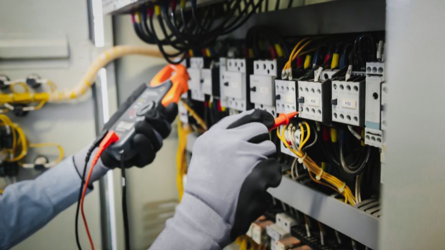 Elektromonter sprawdza napięcie w rozdzielnicy instalacji elektrycznej