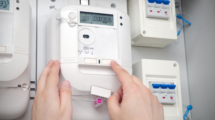 Instalatorka sprawdza pobór energii elektrycznej w rozdzielnicy na liczniku energii